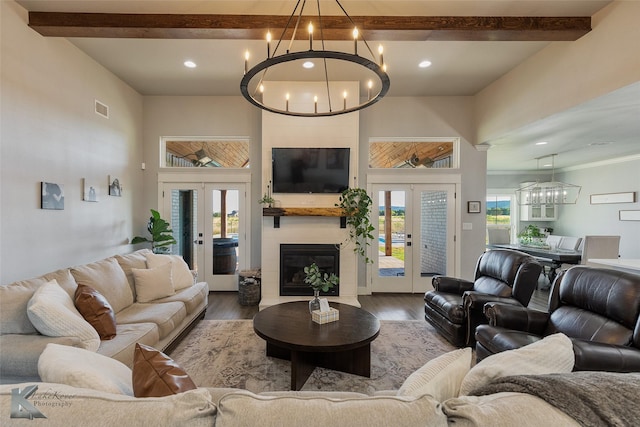 living area with french doors, a notable chandelier, beamed ceiling, and wood finished floors