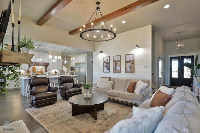 living area featuring wood finished floors, beamed ceiling, a high ceiling, a chandelier, and recessed lighting