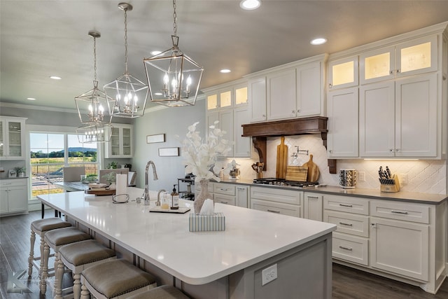 kitchen with ornamental molding, white cabinetry, stainless steel gas stovetop, and under cabinet range hood