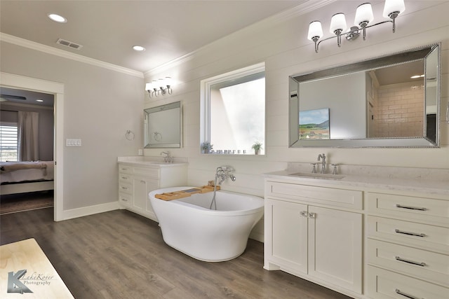 bathroom featuring visible vents, a freestanding bath, ornamental molding, a sink, and wood finished floors