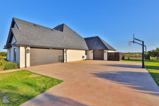 view of home's exterior featuring a shingled roof, a lawn, concrete driveway, an attached garage, and fence