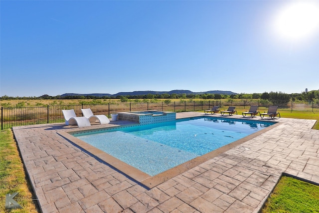 view of swimming pool with a pool with connected hot tub, fence, a mountain view, and a patio