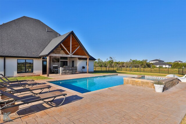 view of swimming pool with a pool with connected hot tub, fence, outdoor dry bar, and a patio