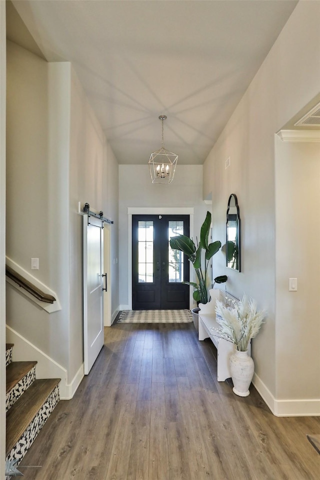 entryway featuring wood finished floors, baseboards, french doors, stairway, and an inviting chandelier