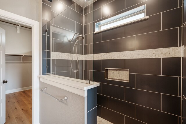 bathroom featuring tiled shower, wood-type flooring, and tile walls