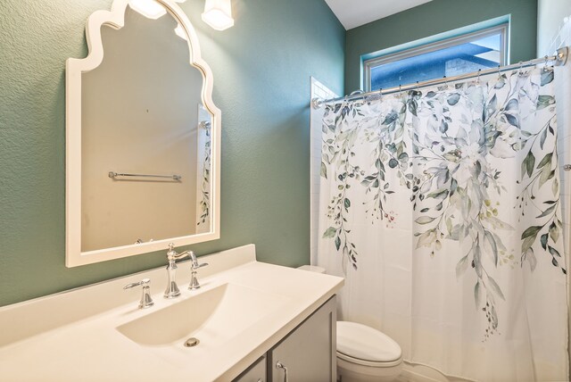 bathroom featuring a shower with shower curtain, toilet, and vanity