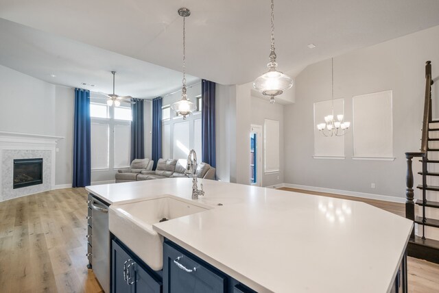 kitchen with a kitchen island with sink, light hardwood / wood-style flooring, and decorative light fixtures