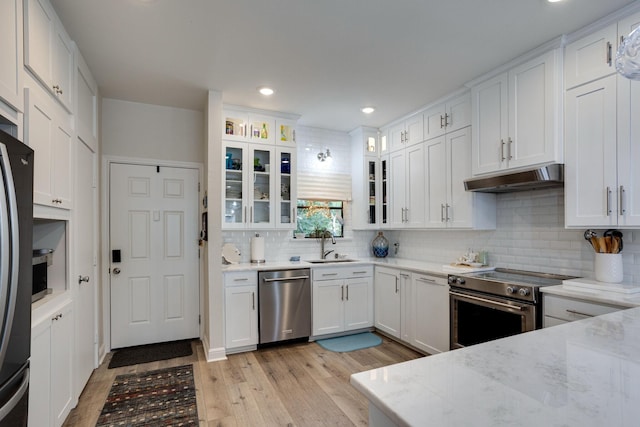 kitchen featuring white cabinetry, sink, stainless steel appliances, light stone counters, and backsplash