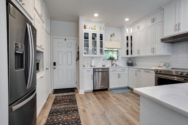 kitchen featuring white cabinets, sink, light hardwood / wood-style floors, light stone counters, and stainless steel appliances