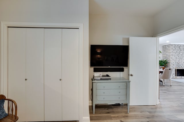 bedroom with light hardwood / wood-style floors and brick wall