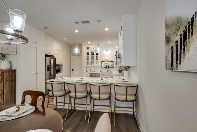 kitchen featuring kitchen peninsula, white cabinets, stainless steel appliances, and dark hardwood / wood-style floors