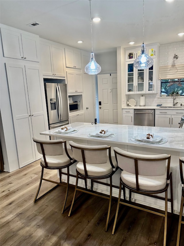 kitchen with a kitchen breakfast bar, white cabinetry, and appliances with stainless steel finishes