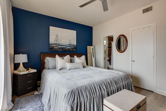 bedroom with ensuite bathroom, ceiling fan, and light wood-type flooring