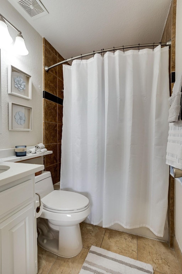 bathroom with vanity, toilet, and a textured ceiling