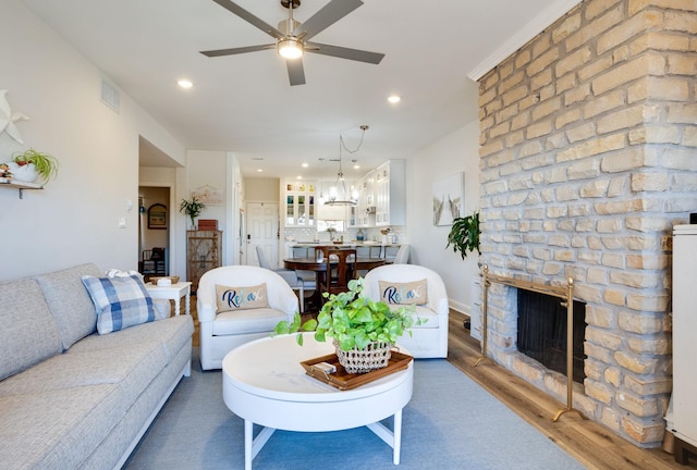 living room with a brick fireplace, ceiling fan, and dark wood-type flooring