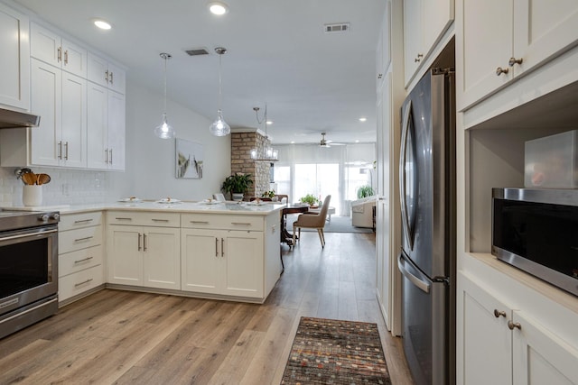 kitchen with kitchen peninsula, tasteful backsplash, stainless steel appliances, ceiling fan, and decorative light fixtures