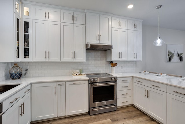 kitchen featuring stainless steel range with electric stovetop, white cabinetry, hanging light fixtures, and tasteful backsplash