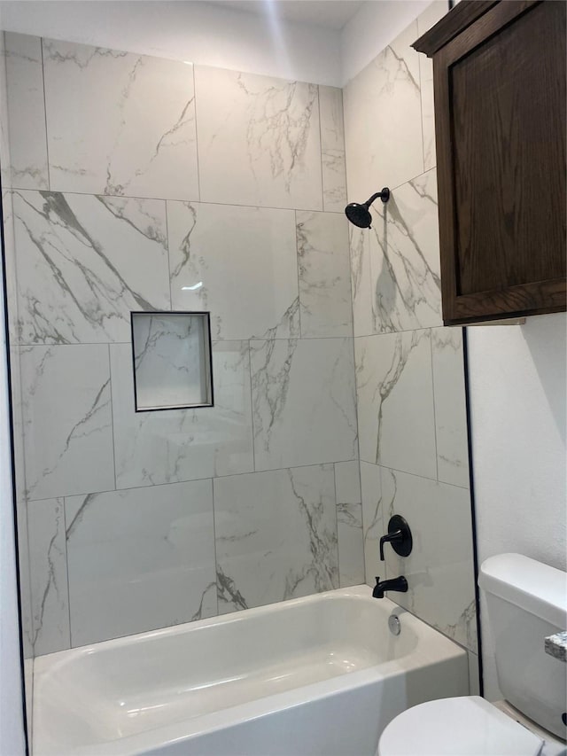 bathroom featuring toilet and tiled shower / bath