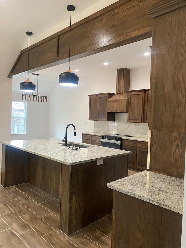 kitchen featuring pendant lighting, custom exhaust hood, electric stove, sink, and light stone counters