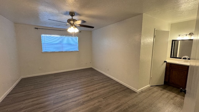 unfurnished bedroom featuring ceiling fan, sink, a textured ceiling, dark wood-type flooring, and ensuite bathroom