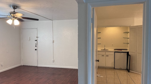 interior space with light wood-type flooring, a textured ceiling, sink, and ceiling fan