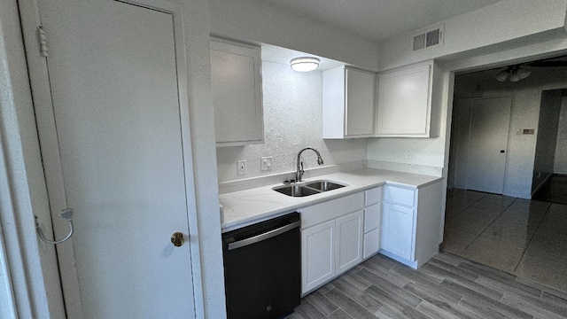 kitchen with black dishwasher, light wood-type flooring, sink, and white cabinetry