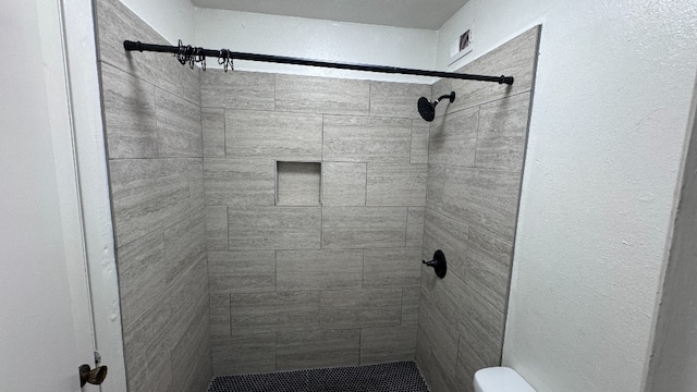 bathroom featuring toilet and tiled shower