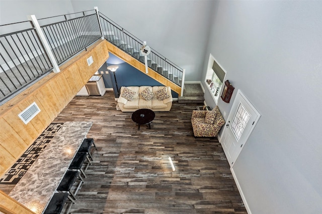 unfurnished living room featuring stairway, a high ceiling, wood finished floors, and baseboards