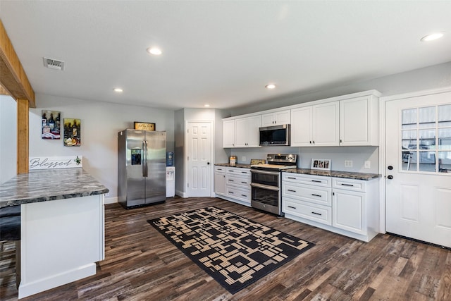 kitchen with dark countertops, dark wood finished floors, white cabinetry, recessed lighting, and stainless steel appliances