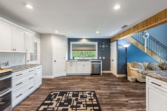 kitchen featuring dark stone counters, dark wood-type flooring, stainless steel dishwasher, white cabinetry, and stove