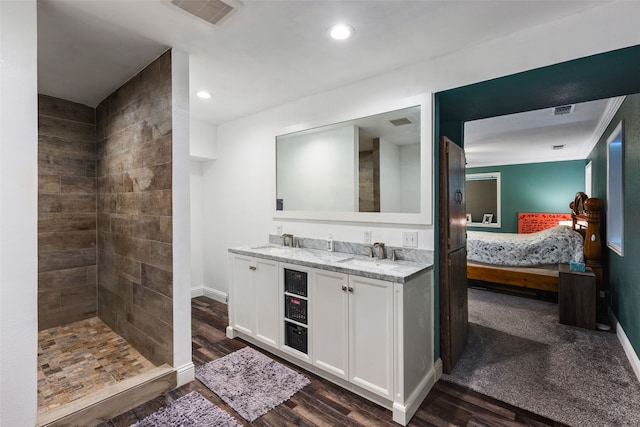 bathroom featuring hardwood / wood-style flooring, a tile shower, and vanity