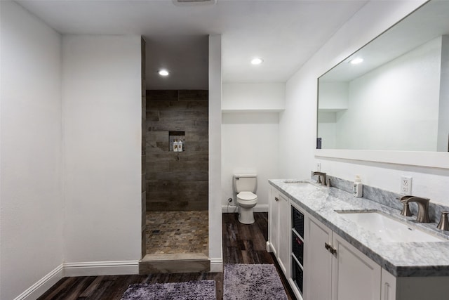 bathroom featuring toilet, hardwood / wood-style floors, vanity, and tiled shower