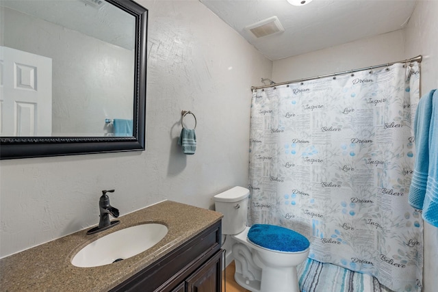 full bath with visible vents, curtained shower, toilet, a textured wall, and vanity