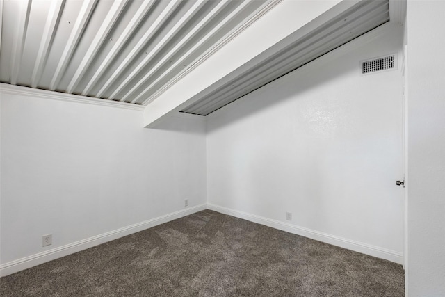 empty room featuring baseboards, visible vents, and dark colored carpet