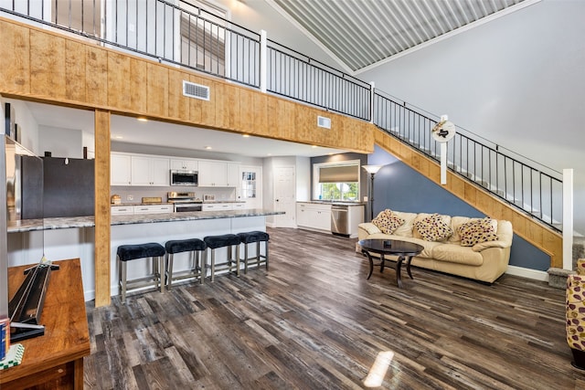 living room with dark hardwood / wood-style flooring, high vaulted ceiling, and crown molding