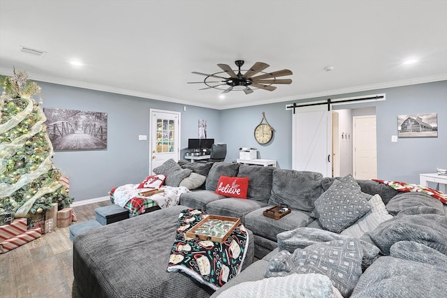 living room with ceiling fan, crown molding, wood-type flooring, and a barn door