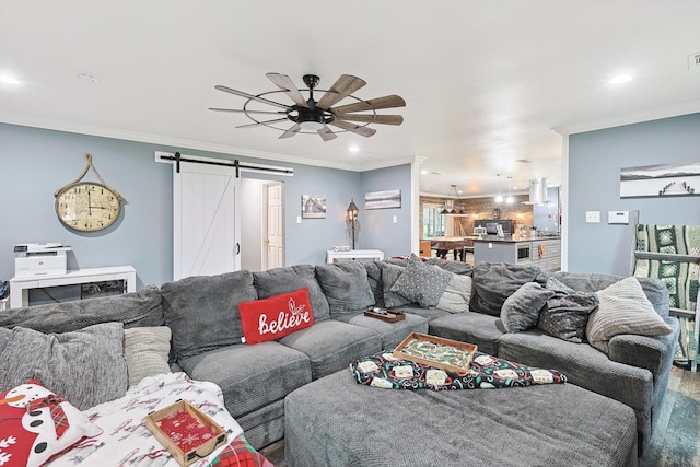 living room featuring ceiling fan, crown molding, and a barn door