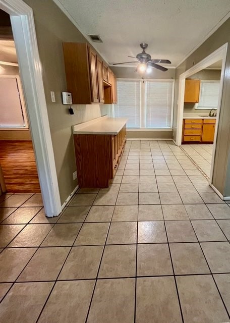 kitchen featuring crown molding, ceiling fan, sink, and light tile patterned floors