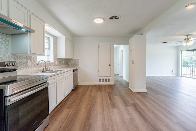 kitchen featuring decorative backsplash, light hardwood / wood-style flooring, white cabinetry, exhaust hood, and stainless steel appliances