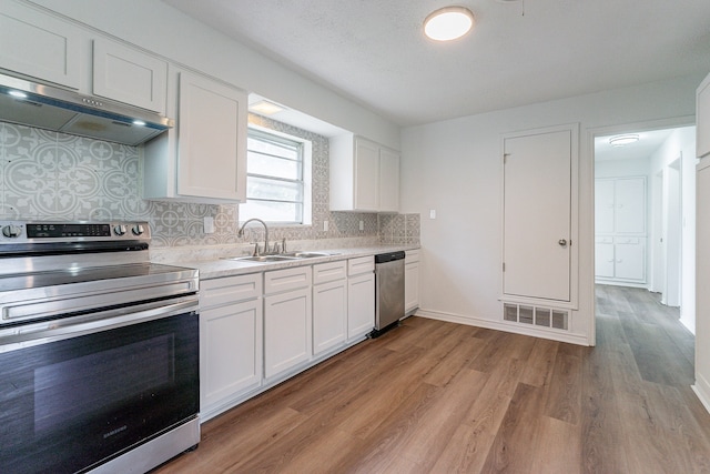 kitchen featuring appliances with stainless steel finishes, backsplash, light hardwood / wood-style floors, white cabinetry, and sink