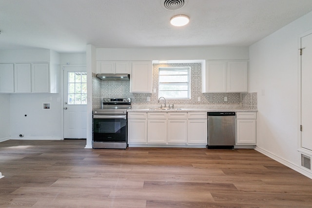 kitchen with sink, stainless steel appliances, white cabinetry, and light wood-type flooring