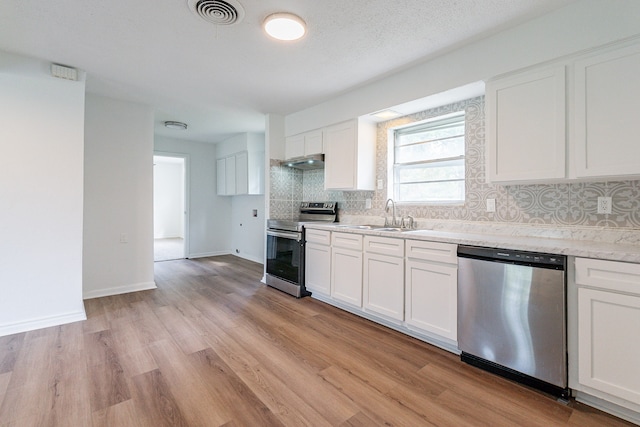 kitchen featuring sink, appliances with stainless steel finishes, light hardwood / wood-style flooring, decorative backsplash, and white cabinetry