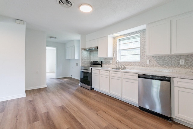 kitchen with stainless steel appliances, visible vents, backsplash, white cabinetry, and a sink