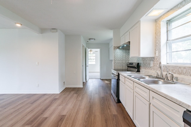 kitchen with stainless steel electric stove, plenty of natural light, and light hardwood / wood-style floors