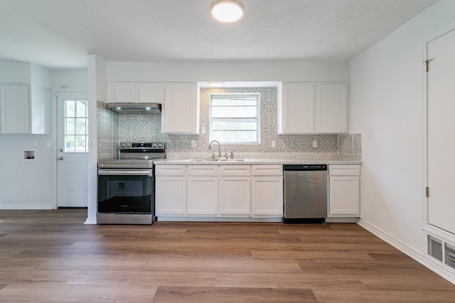 kitchen featuring light hardwood / wood-style flooring, backsplash, white cabinetry, appliances with stainless steel finishes, and sink