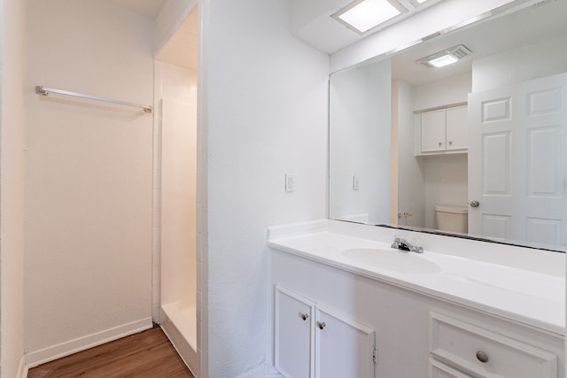 bathroom with a shower, vanity, hardwood / wood-style floors, and toilet