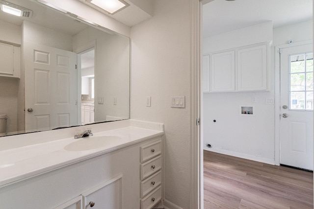 bathroom with visible vents, wood finished floors, vanity, and baseboards