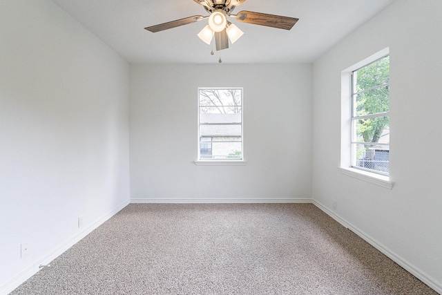 carpeted spare room with a ceiling fan, plenty of natural light, and baseboards