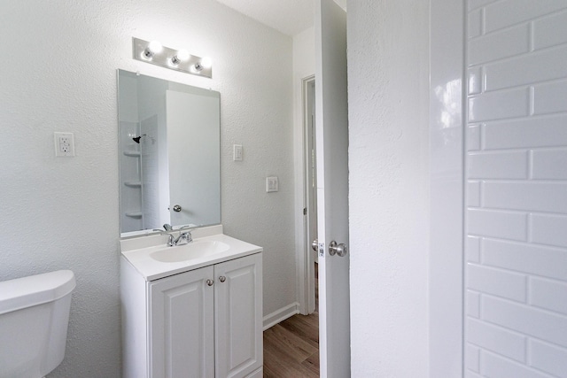 bathroom with a shower, vanity, toilet, and wood finished floors