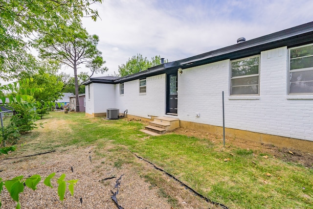 back of house featuring central AC unit and a yard